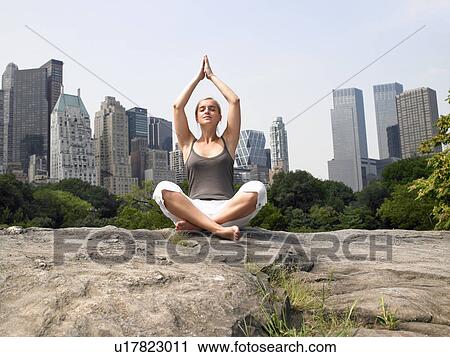 Stock Image - Woman doing yoga in central park. Fotosearch