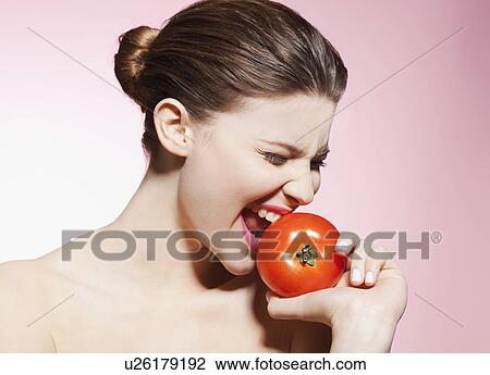 Stock Image - Woman eating a tomato. Fotosearch