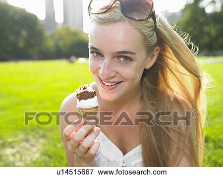 Woman eating an ice cream in a park View Large Photo Image Stock Photo - Woman eating an ice cream in a park. Fotosearch
