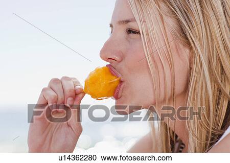 Stock Image - Woman eating popsicle on beach. Fotosearch