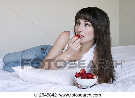 Woman eating strawberries on bed View Large Photo Image Stock Image - Woman eating strawberries on bed. Fotosearch