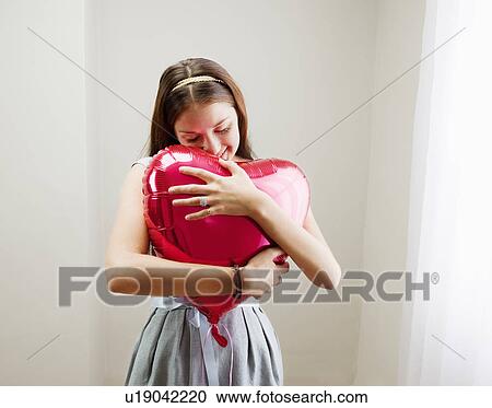 Woman embracing heart shaped balloon View Large Photo Image Stock Image - Woman embracing heart shaped balloon. Fotosearch