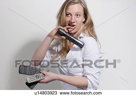 Stock Image - Woman holding different remote controls. Fotosearch