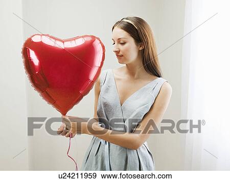 Stock Photo - Woman holding heart shaped balloon. Fotosearch