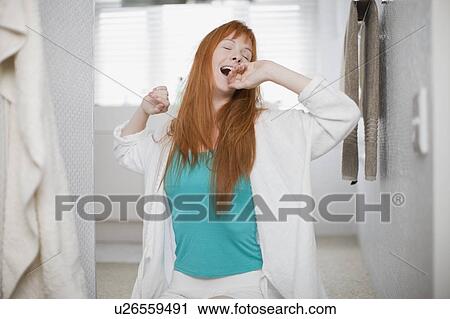 Stock Image - Woman in bathrobe yawning and stretching. Fotosearch