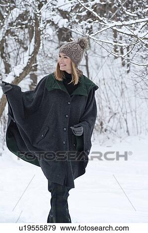 Stock Photo - Woman in heavy cape walking in snow. Fotosearch