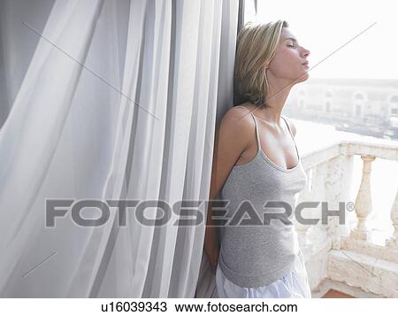 Stock Image - Woman in her pyjamas, on the balcony. Fotosearch