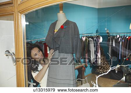 Stock Photo - woman in shop window dressing mannequin. Fotosearch