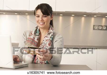 Stock Image - Woman in the kitchen buying on internet. Fotosearch