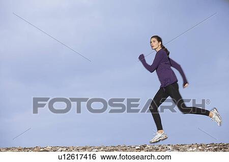 woman jogging along pebble beach View Large Photo Image Stock Photograph - woman jogging along pebble beach. Fotosearch
