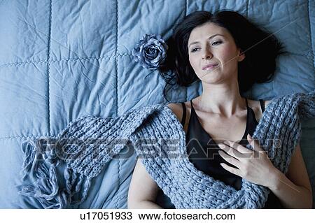 Stock Image - Woman laying on bed dreaming. Fotosearch