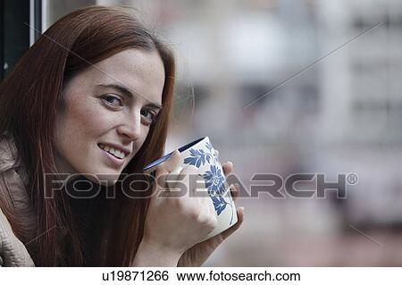 Stock Photograph - Woman leaning out of window holding cup. Fotosearch