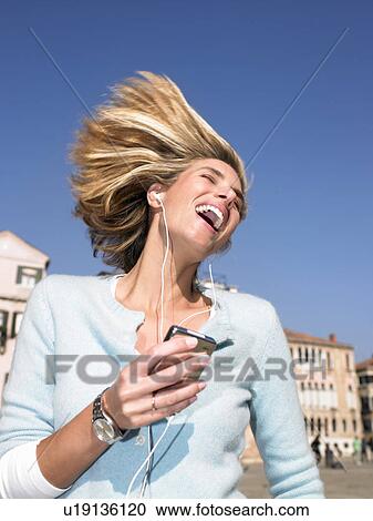 Stock Image - Woman listenning to mp3 player, dancing. Fotosearch