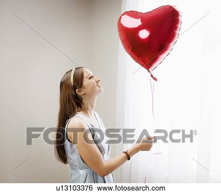 Woman looking at heart shaped balloon View Large Photo Image Stock Photograph - Woman looking at heart shaped balloon. Fotosearch