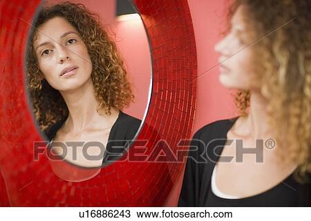 Stock Image - Woman looking at herself in mirror. Fotosearch