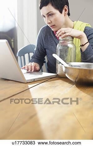 Woman looking at laptop whilst cooking View Large Photo Image Stock Image - Woman looking at laptop whilst cooking. Fotosearch