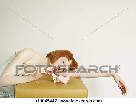 Stock Image - woman looking at origami swan. Fotosearch