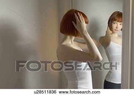 Stock Photograph - woman looking at reflection in mirror. Fotosearch