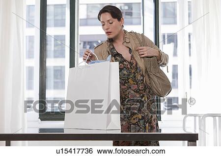 Stock Photograph - woman looking in shopping bag. Fotosearch