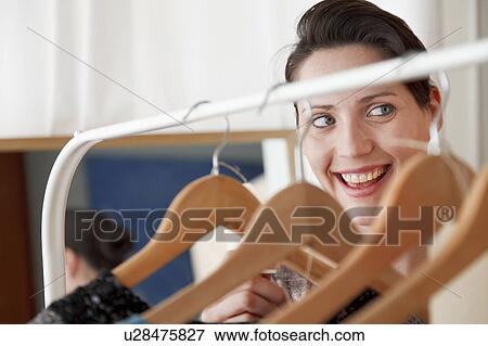 Stock Photo - woman looking through coat hangers. Fotosearch