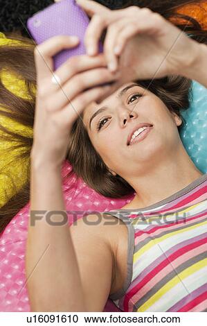 Woman lying and checking her phone View Large Photo Image Stock Image - Woman lying and checking her phone. Fotosearch