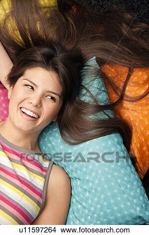 Picture - Woman lying on cushions and laughing. Fotosearch