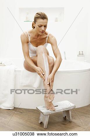 Stock Photo - Woman moisturizing her legs. Fotosearch