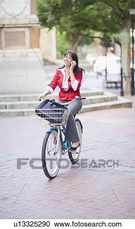 Woman on a bicycle making a phone call View Large Photo Image Stock Image - Woman on a bicycle making a phone call. Fotosearch