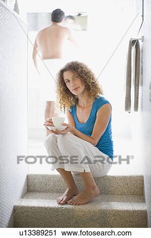 Stock Image - Woman on steps drinking coffee. Fotosearch