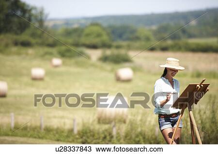 Stock Image - Woman painting a picture, outdoors. Fotosearch