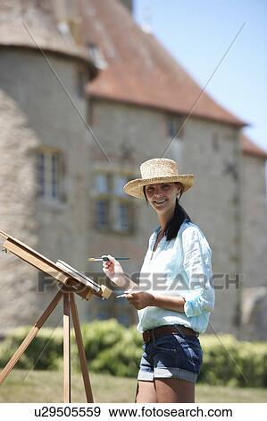 Stock Photo - Woman painting a picture, outdoors. Fotosearch