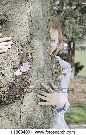 Woman peeking out from behind tree View Large Photo Image Stock Photo - Woman peeking out from behind tree. Fotosearch