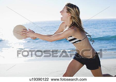 Stock Image - Woman playing tennis on beach. Fotosearch