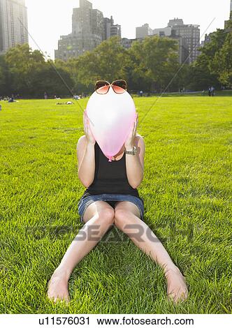 Stock Image - Woman playing with a balloon in a park. Fotosearch