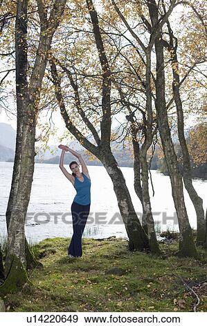 Stock Photo - woman practising yoga position amongst trees. Fotosearch