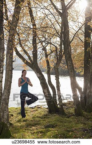 Stock Photography - woman practising yoga position amongst trees. Fotosearch