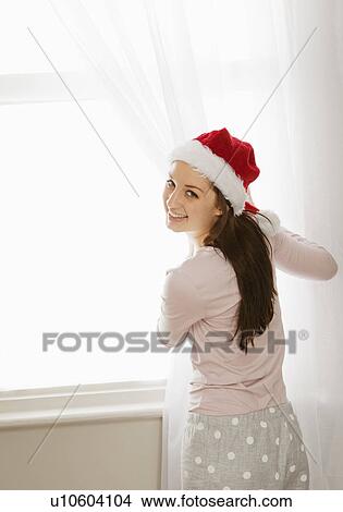 Picture - Woman pulling curtains aside, laughing. Fotosearch