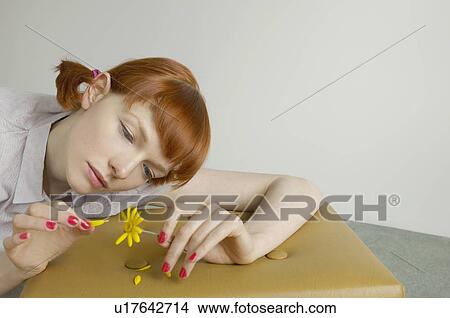 Picture - woman pulling petals from daisy. Fotosearch