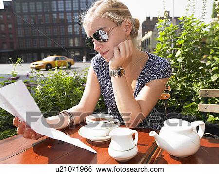 Stock Photograph - Woman reading a letter at a cafe. Fotosearch