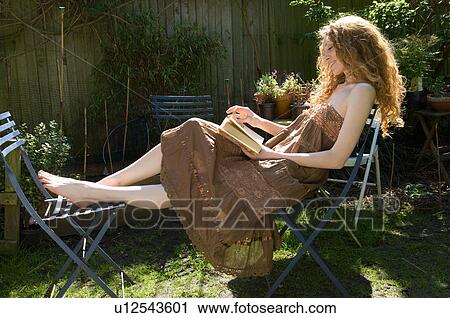 Woman reading book in backyard View Large Photo Image Stock Image - Woman reading book in backyard. Fotosearch