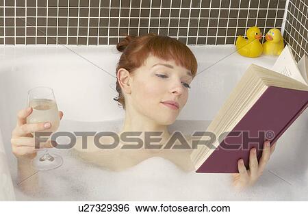 Stock Photograph - woman relaxing in bath with book. Fotosearch