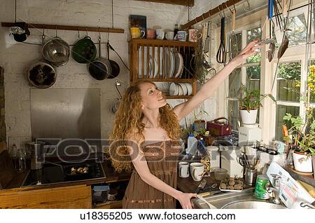 Stock Photography - Woman selecting utensil in kitchen. Fotosearch
