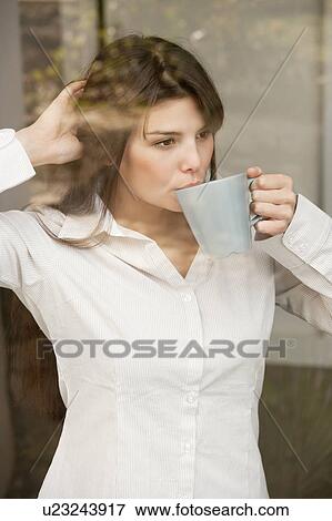 Stock Photo - Woman shot through a window drinking tea. Fotosearch