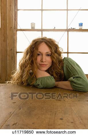 Stock Image - Woman sitting at kitchen table. Fotosearch