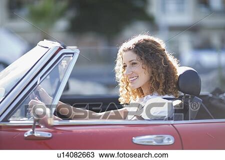 Stock Image - Woman sitting in a convertible car. Fotosearch