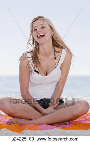 Woman sitting on towel at beach View Large Photo Image Stock Photo - Woman sitting on towel at beach. Fotosearch