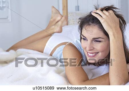 Stock Photo - Woman smiling and laying on a bed. Fotosearch