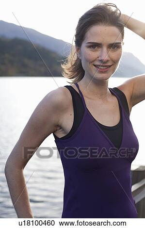 Stock Image - woman standing in front of lake at sunrise. Fotosearch