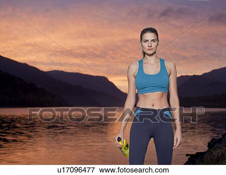 woman standing in front of lake with water bottle at sunrise View Large Photo Image Stock Photo - woman standing in front of lake with water bottle at sunrise. Fotosearch