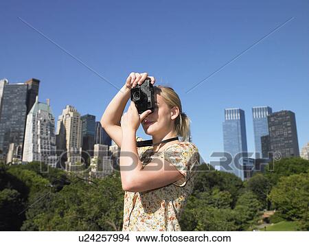 Picture - Woman taking pictures in central park. Fotosearch